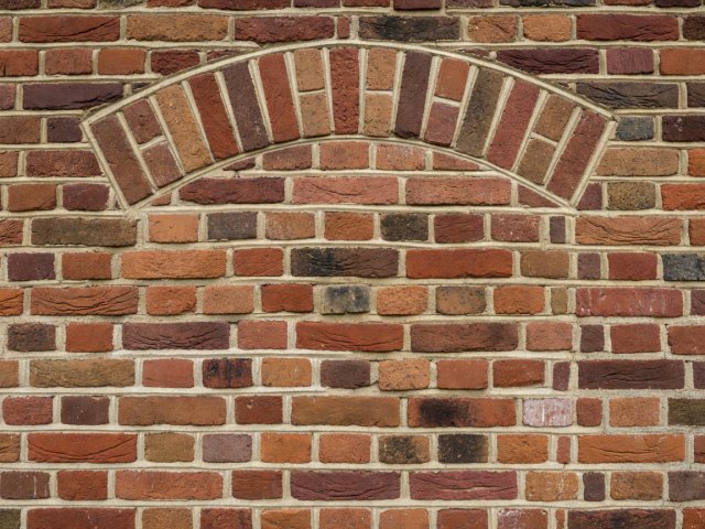 Detail of old brickwork with an infilled arch and newer mortar joints in a lighter colour